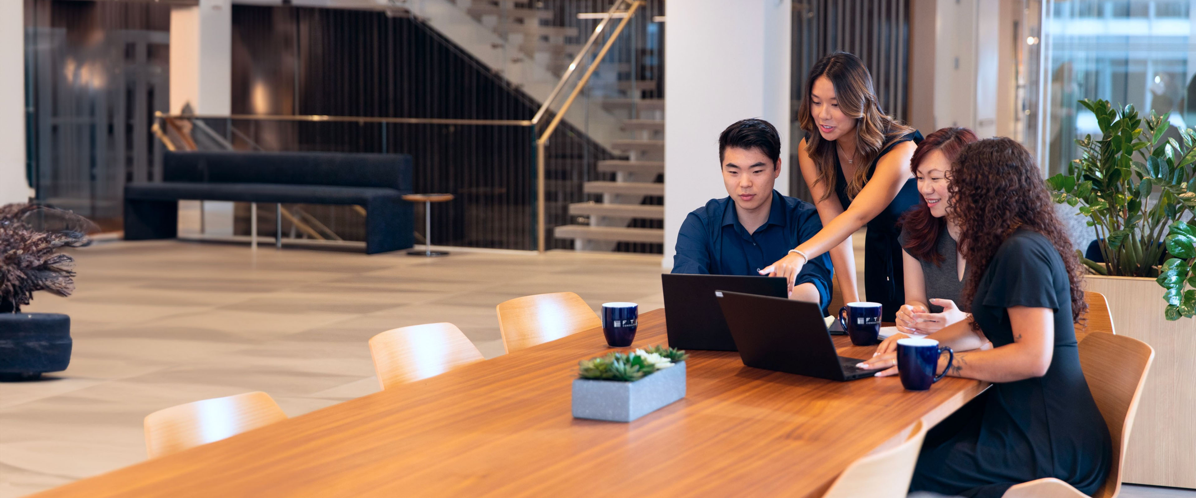 Employees Sitting at Table Looking at Laptops