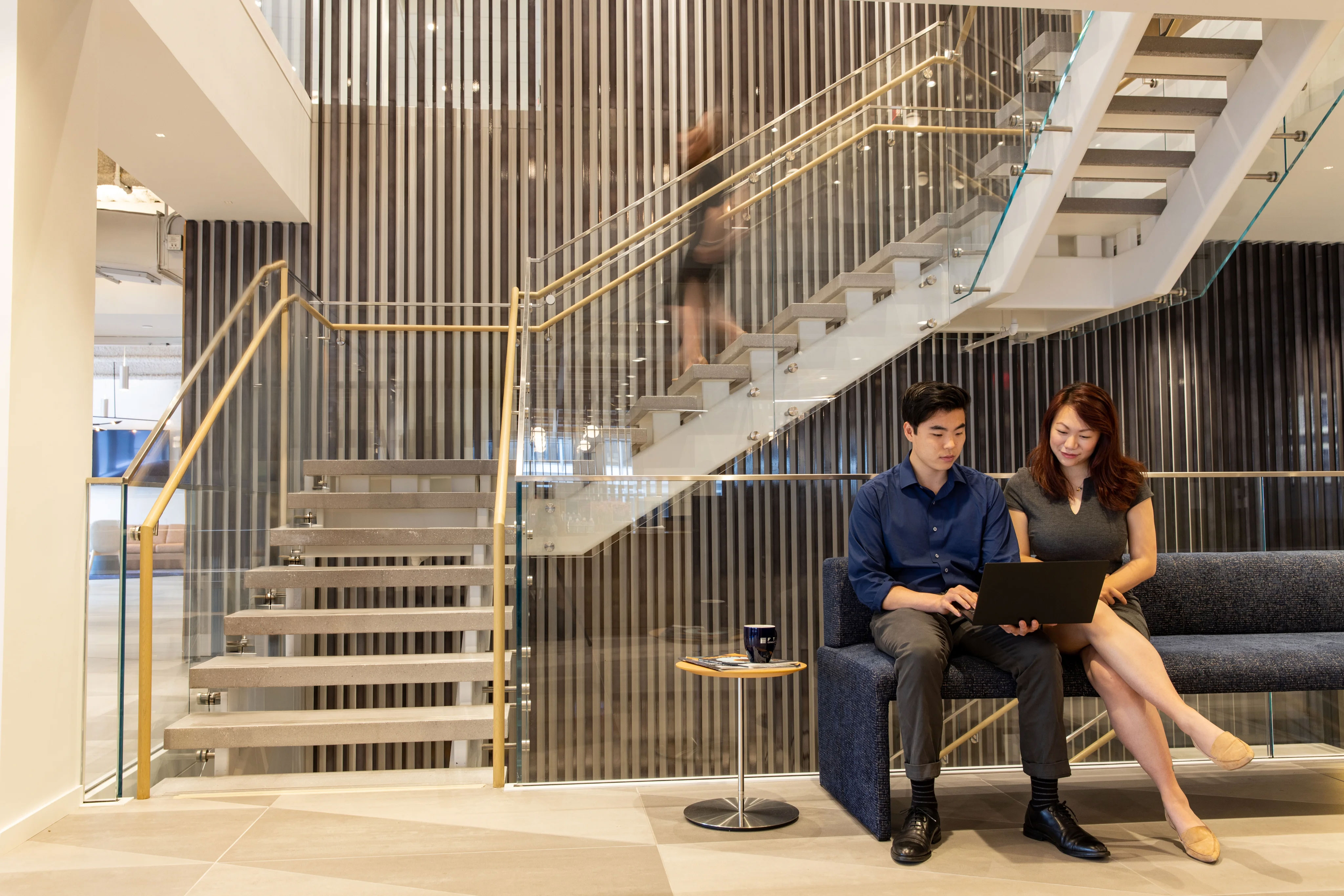 Two professionals on a bench with a large staircase behind them